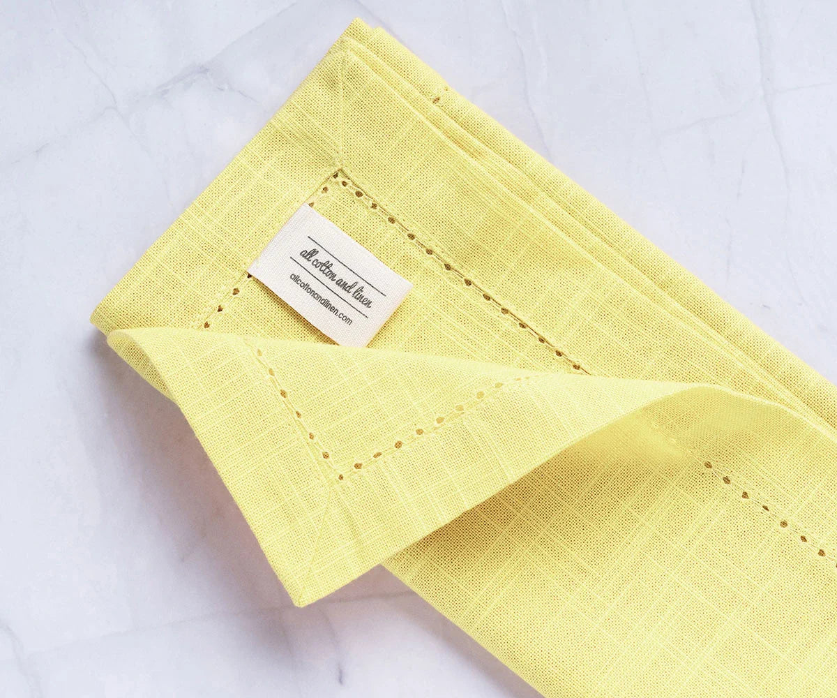 Servilletas de color amarillo mantequilla con dobladillo
